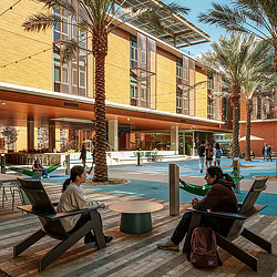 A couple of people sitting on a bench in front of a building.