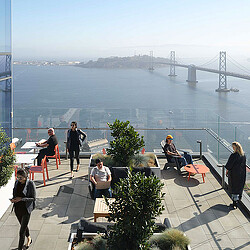 A group of people sitting on a balcony overlooking a body of water.